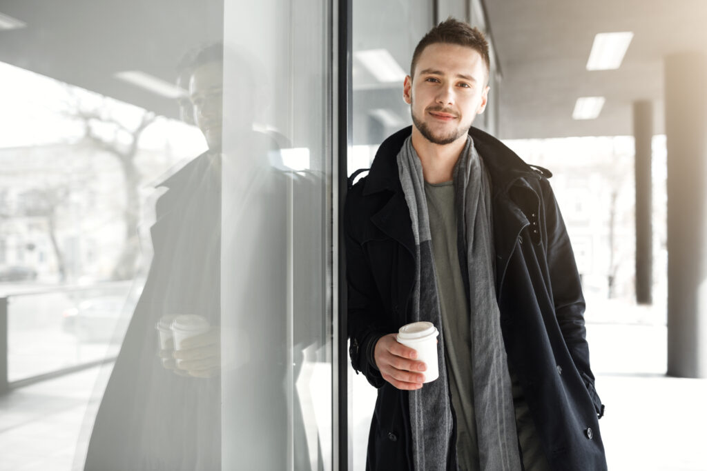 guy in cool spring clothes relaxing while drinking cooffee outside.